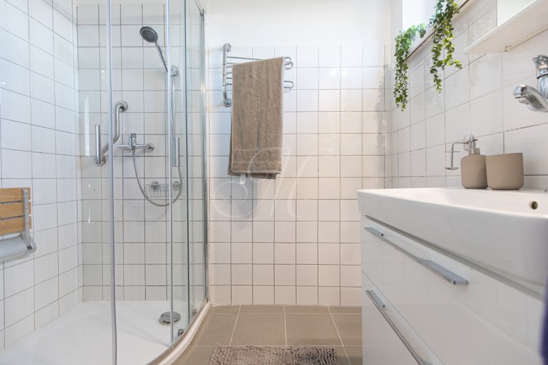 A bathroom in a 3-room apartment with white tiles and a shower corner.