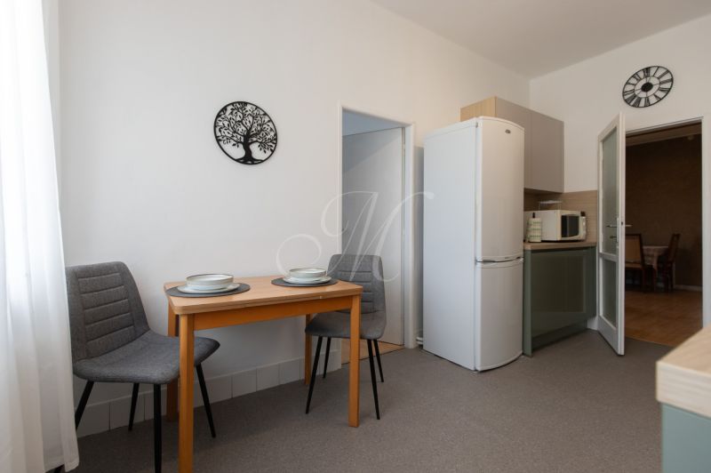 A dining table with two chairs and kitchen appliances in a 3-room apartment.