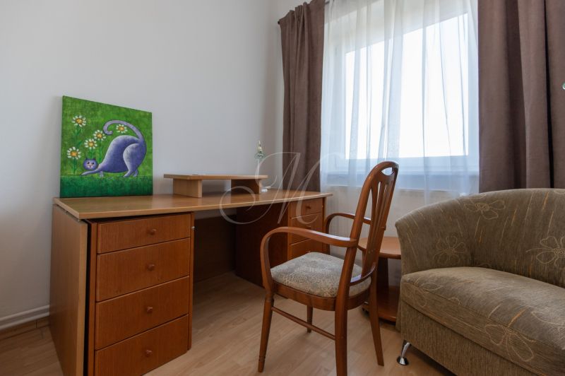 A desk with a chair and a painting in a 3-room apartment, floor with wooden decor.