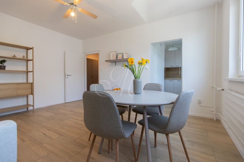 A dining room with a wooden decor floor, a round table, and chairs in a two-room apartment.