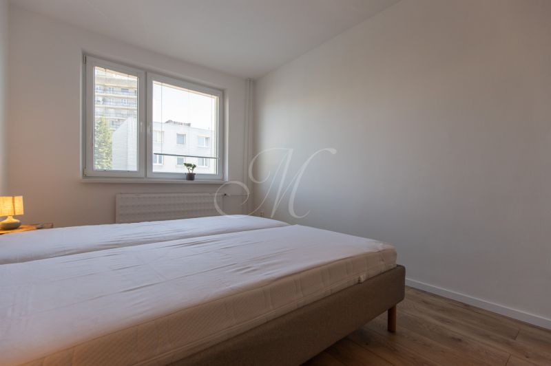 A bedroom with two single beds, a lamp, and a wooden floor in a two-room apartment.