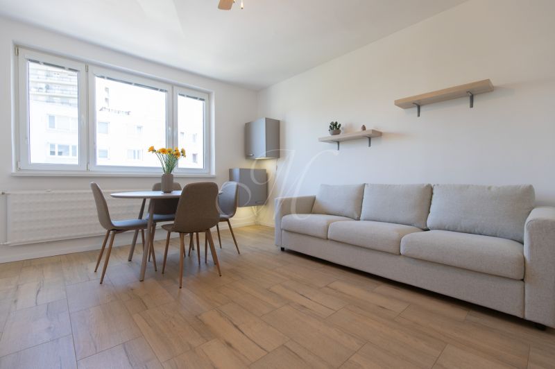 Living room with a dining table, sofa, and wooden decor flooring in a 2-room apartment.