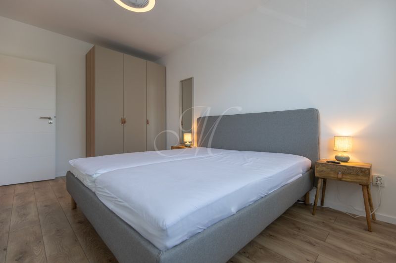 Bedroom with a large bed, wardrobe, and wooden decor flooring in a 2-room apartment.