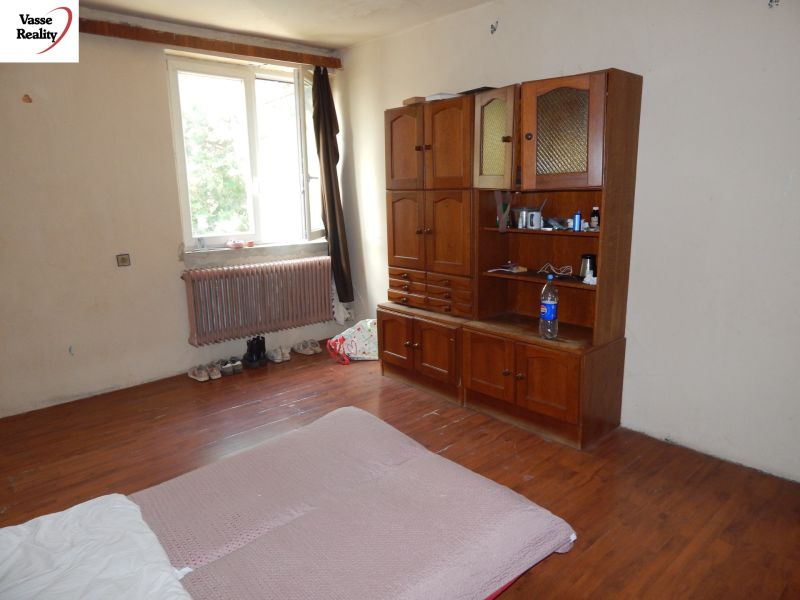 A room in a family house with furniture, a floor with a wooden decor, a window by the radiator.