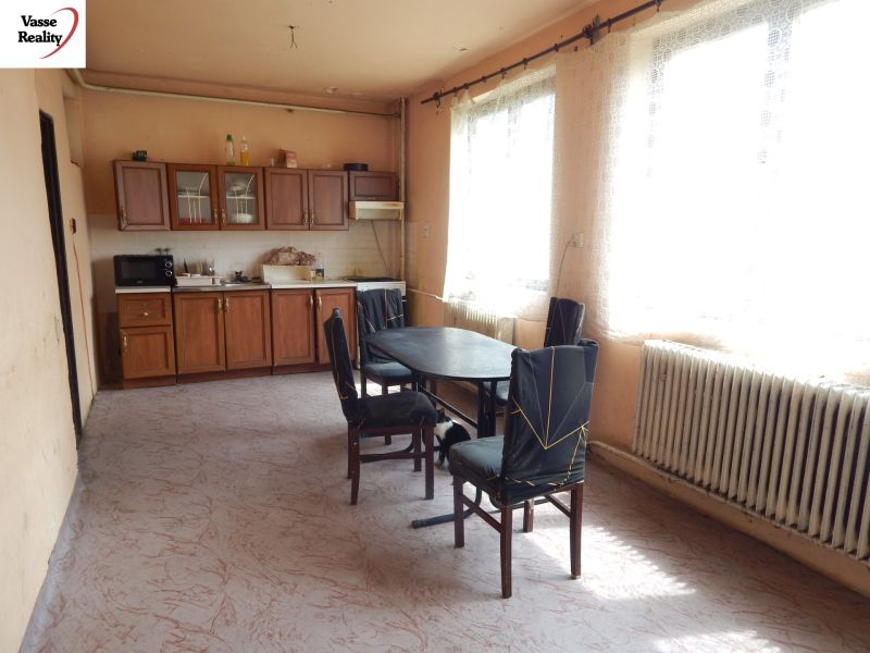 A kitchen in a family house with simple furniture and a radiator under the window.