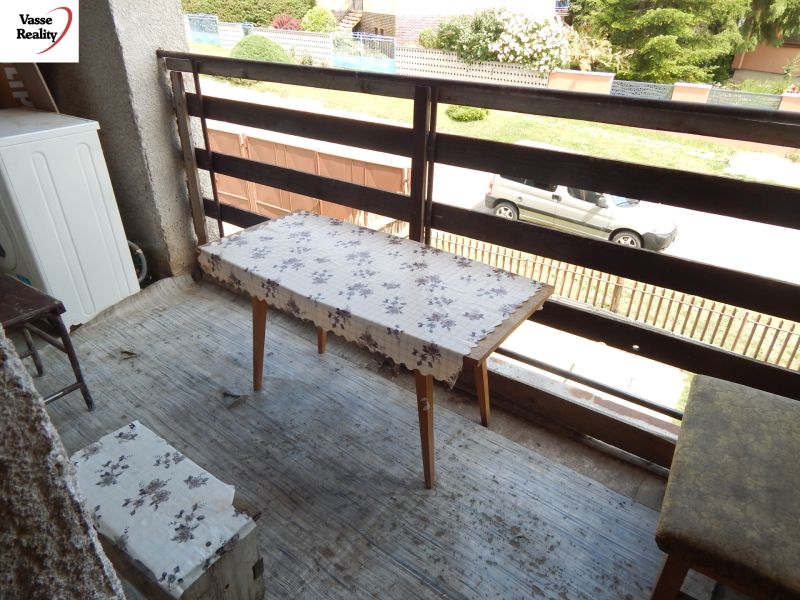 A balcony of a family house in Strekov with a simple table and a view of the garden.