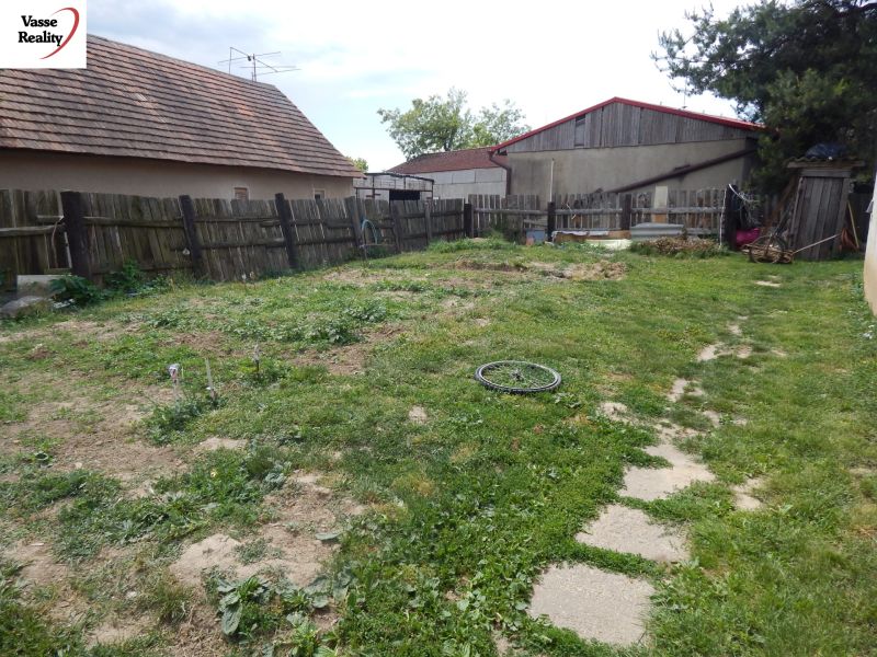A garden at a family house in Strekov with a lawn and a wooden fence.