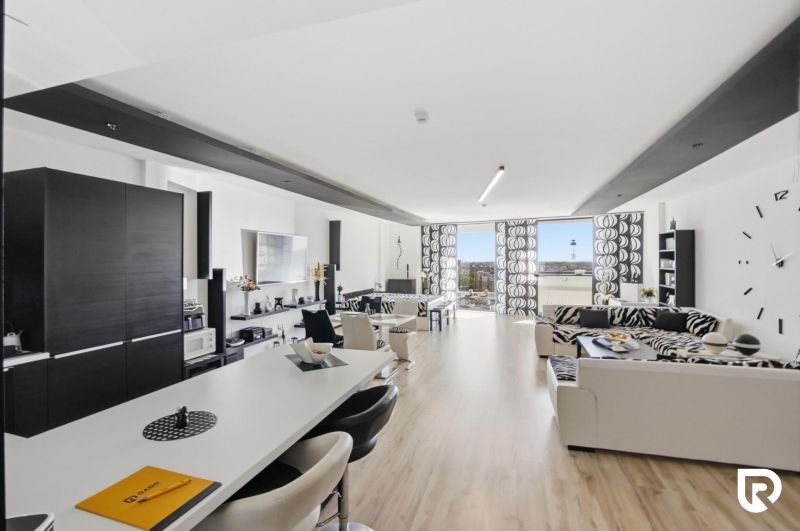 Spacious living area with wood-patterned flooring in a 2-room apartment.