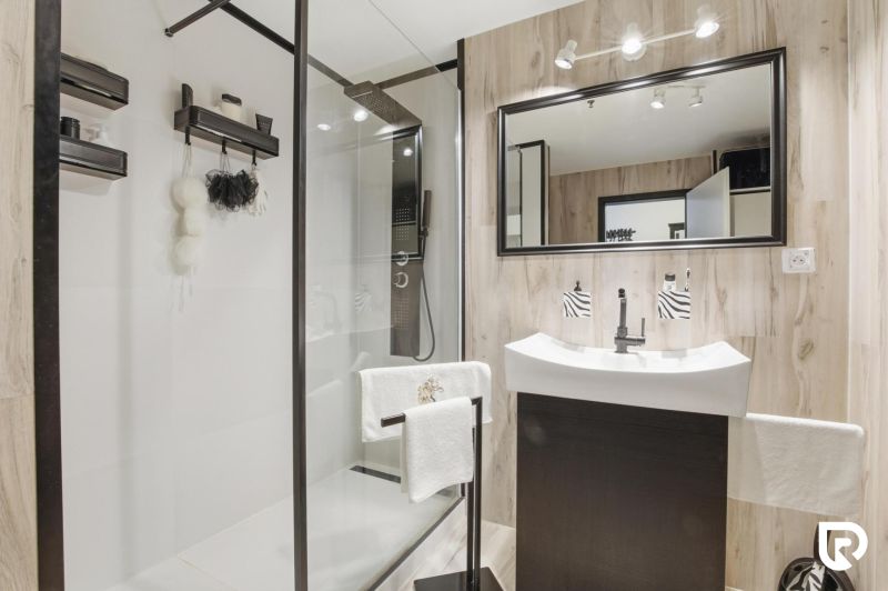 A bathroom in a 2-room apartment with a large mirror and a shower corner.
