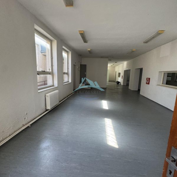 A spacious room with windows and a gray floor in commercial premises.