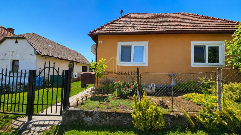 A family house in Demandice with a landscaped garden and a metal fence.