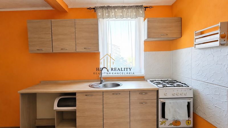 A kitchen in a family house with wooden decor, orange walls, a combination of cabinets and a stove.