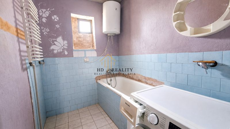 A bathroom in a family house with a bathtub, a washing machine, and purple walls with a butterfly motif.