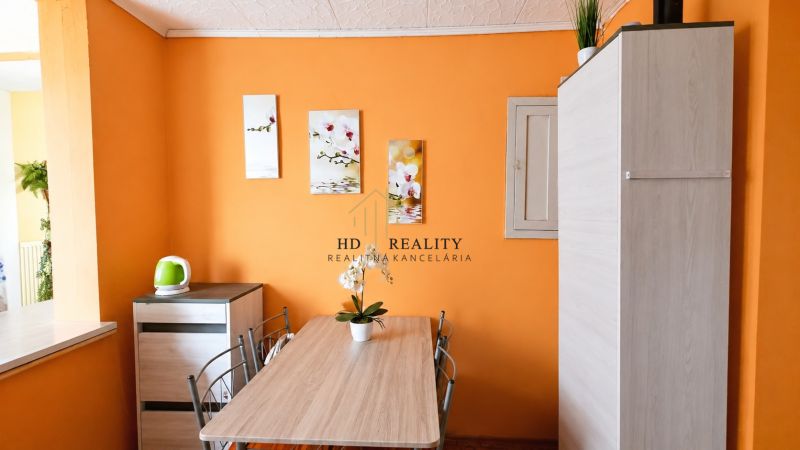 The interior of a family house with an orange wall, a table, and a potted plant.