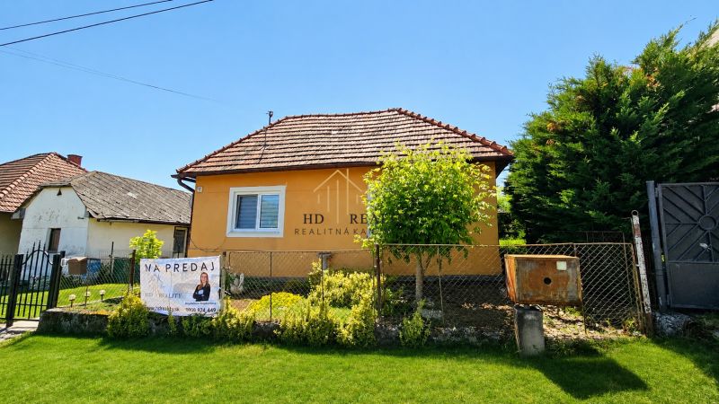 A family house in Demandice with a classic roof, with a front garden behind a fence.