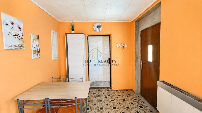 Interior of a family house with orange walls, a table, and decorative paintings.
