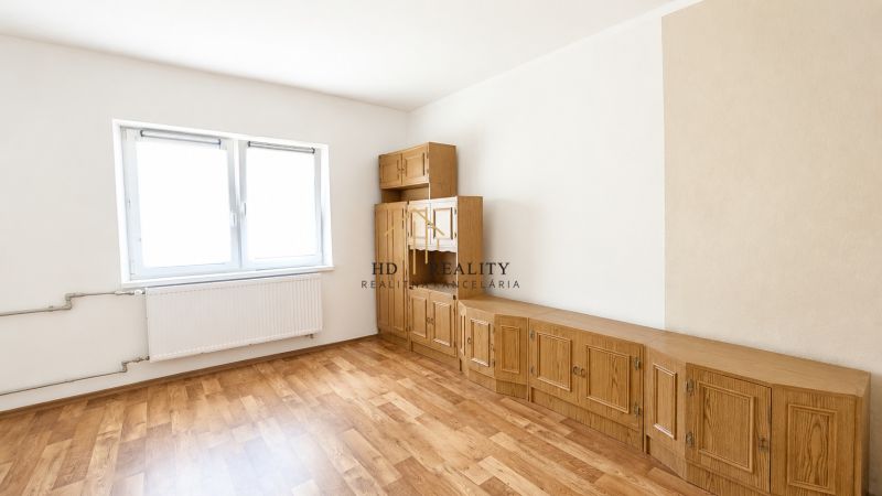 A room in a family house with furniture and a wood-patterned floor.