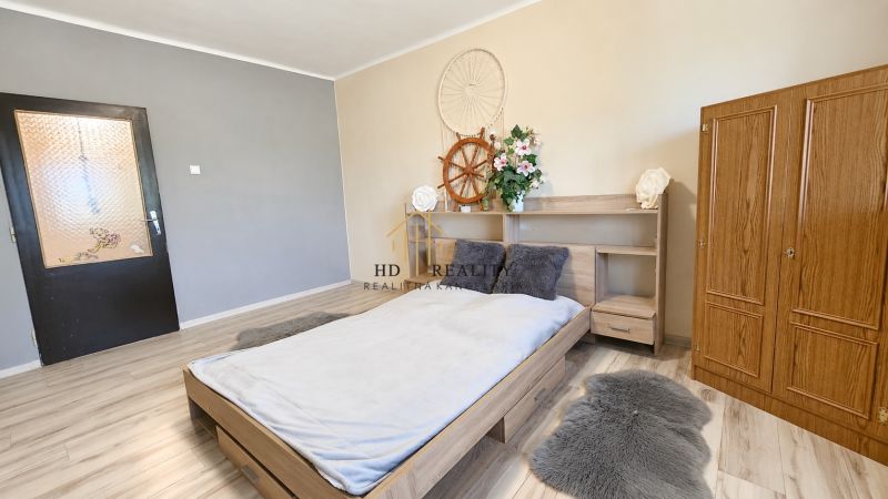 A bedroom in a family house with a bed, a cabinet, and a floor with a wooden decor.