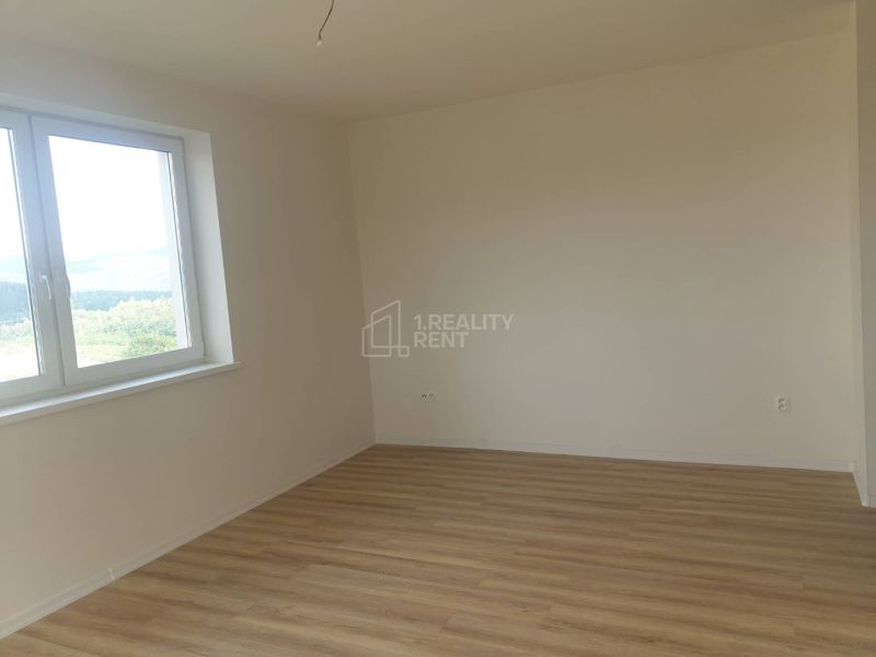 A room in a one-room apartment with white walls and a wooden decor floor.