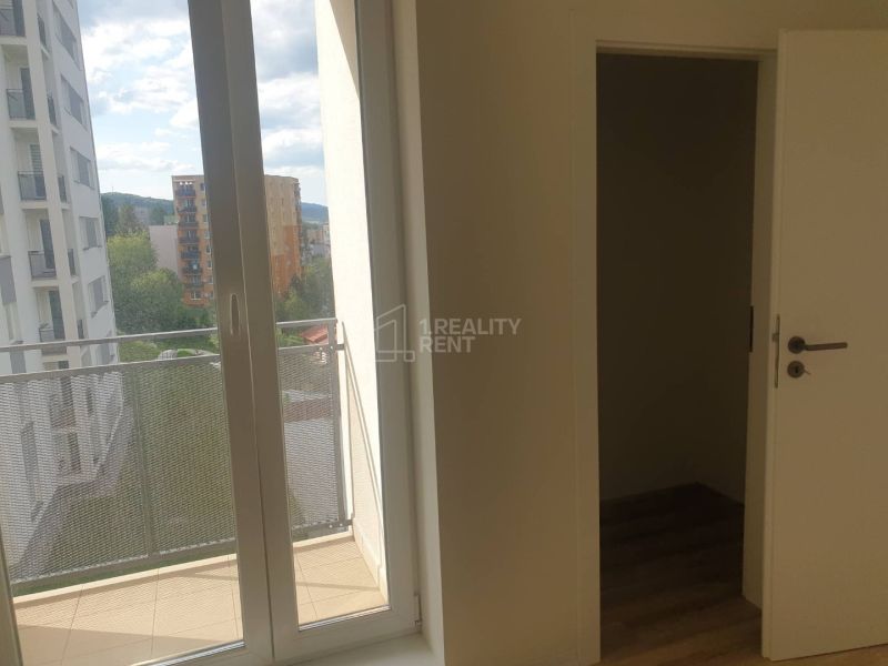 A room in a one-bedroom apartment with a balcony and a floor with a wood decor.
