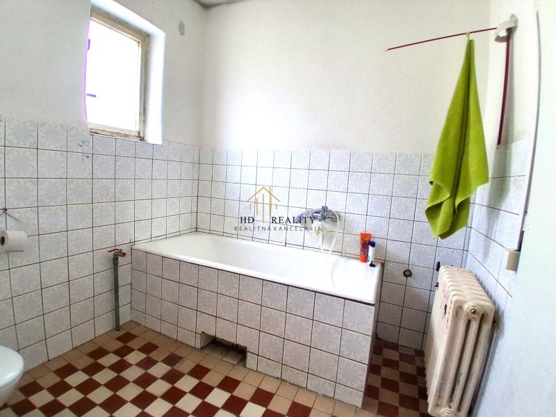 Bathroom in a family house with white tiles and a bathtub.