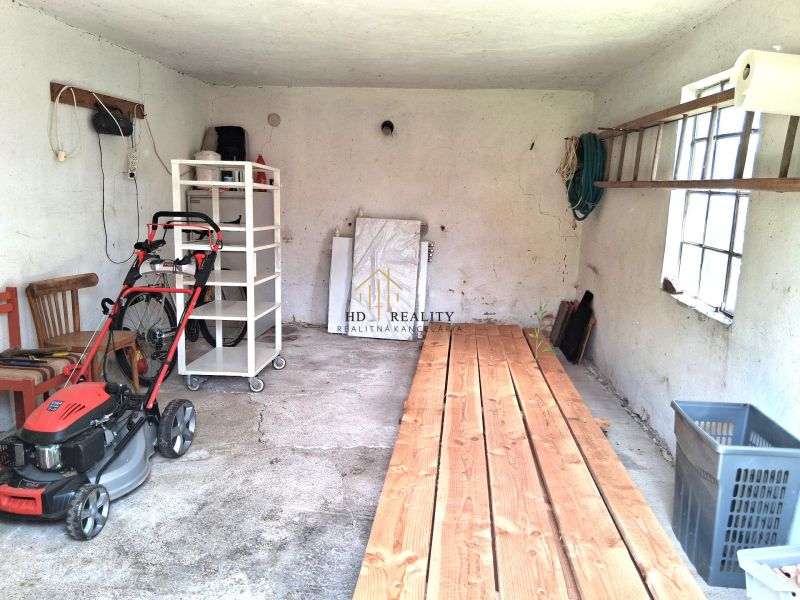 A garage in a family house with tools and a lawnmower on a concrete floor.