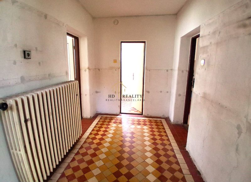 The interior of a family house with a radiator and checkered tile flooring.