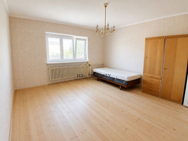 A room in a family house with a bed, a wardrobe, and a floor with a wooden decor.