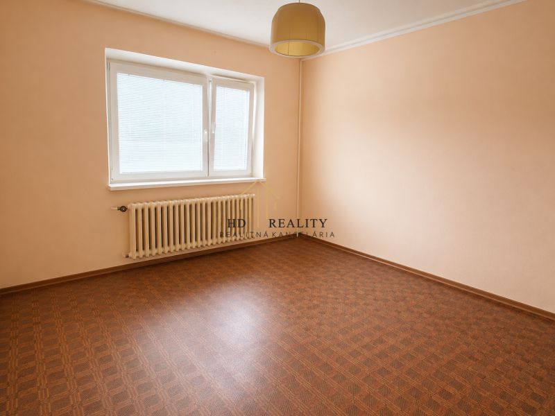 An empty room with a wooden floor and a white radiator.