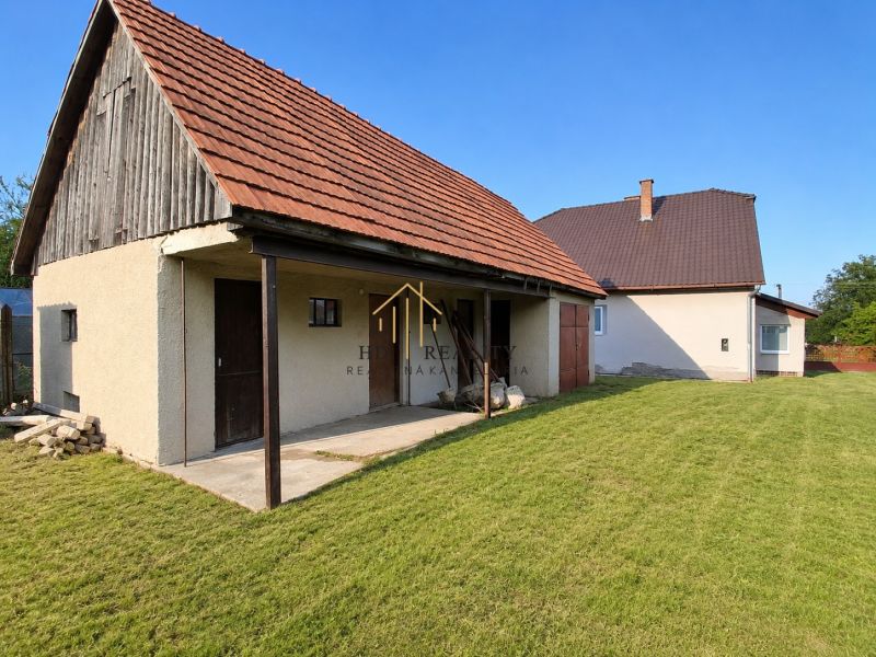 A family house in Sebechleby with a courtyard and a shelter, surrounded by a landscaped grassy area.