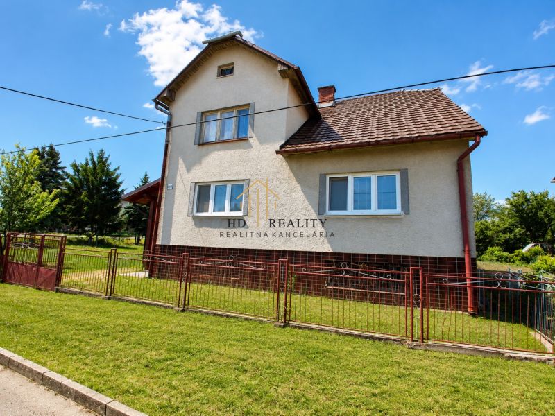 A family house in Sebechleby with a grassy plot and a woven fence.