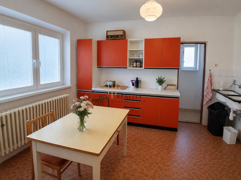 A kitchen in a family house with red cabinets and a table with flowers.