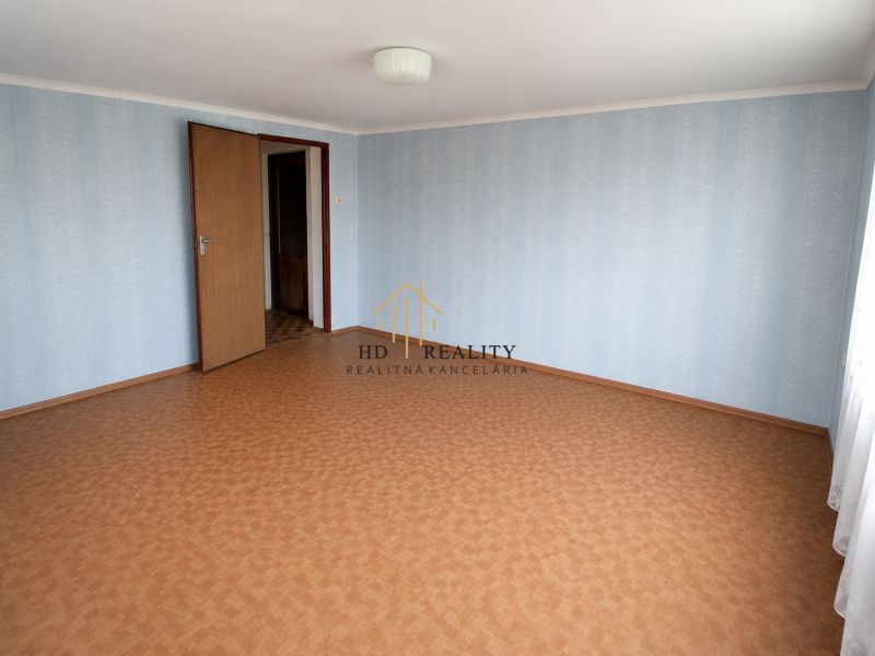 A room in a family house with wallpaper and a wooden decor floor.