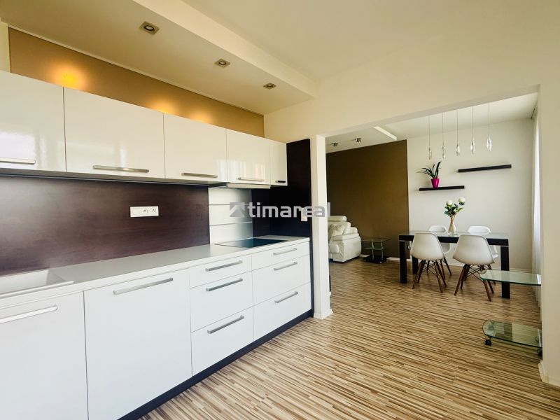 A kitchen with a dining area in a 3-room apartment, with a wooden decor floor.