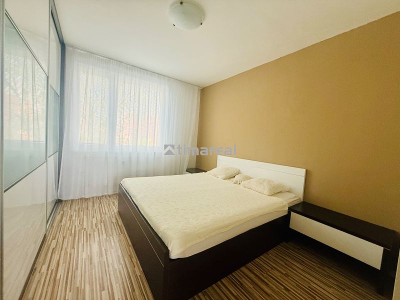 A bedroom in a 3-room apartment with a wood-patterned floor and a built-in wardrobe.