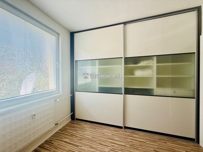A room with a sliding wardrobe and a floor with a wooden decor in a 3-room apartment.