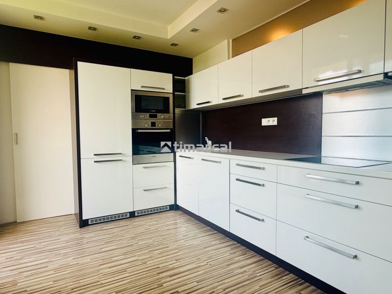 A kitchen in a 3-room apartment with a wooden decor floor and built-in appliances.