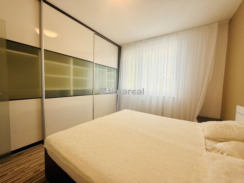 A bright bedroom with a large built-in wardrobe in a 3-room apartment and a floor with a wooden decor.