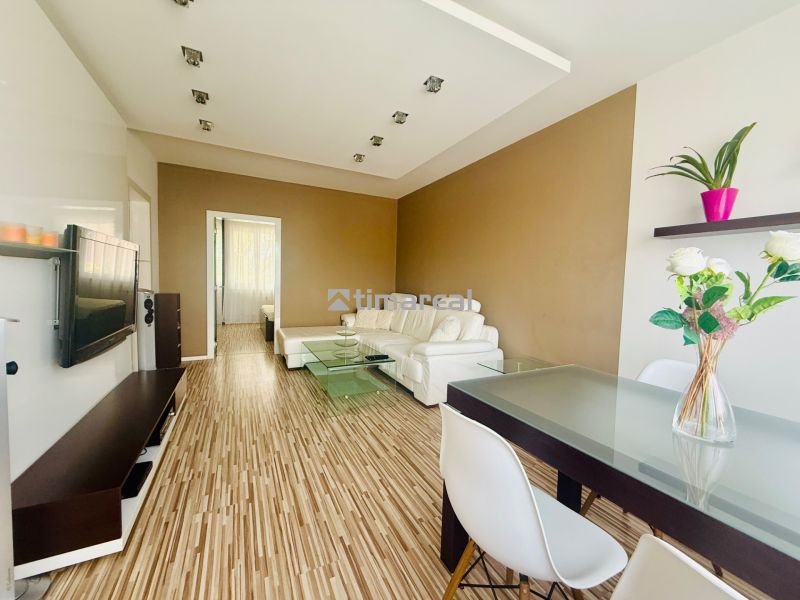 Living room with wood-patterned flooring, light furniture, part of a 3-room apartment.