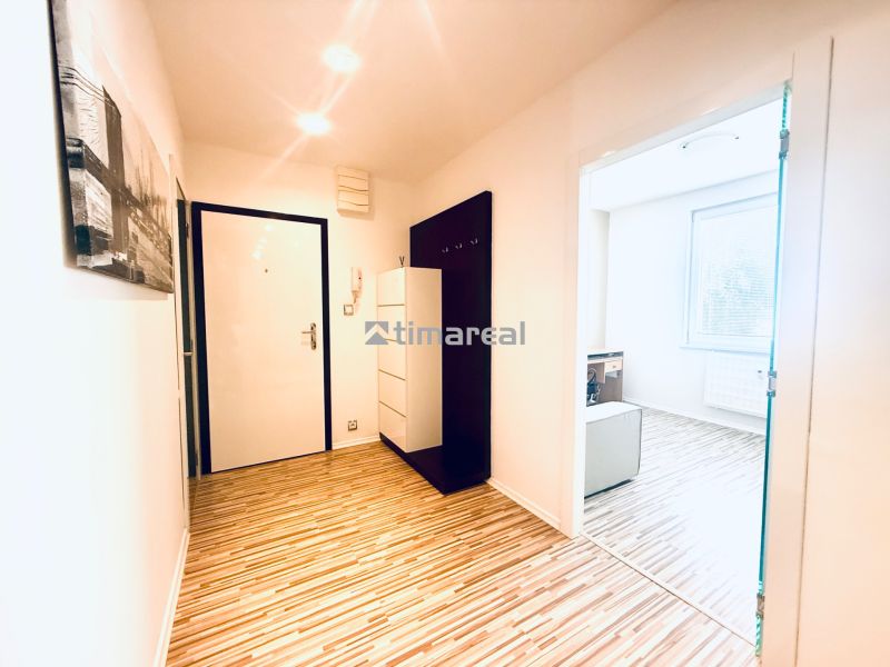 A hallway in a 3-room apartment with a wooden decor floor and a coat rack wall.