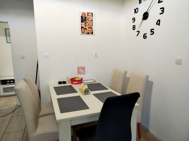Dining area with four chairs and a large clock on the wall in a 2-room apartment.