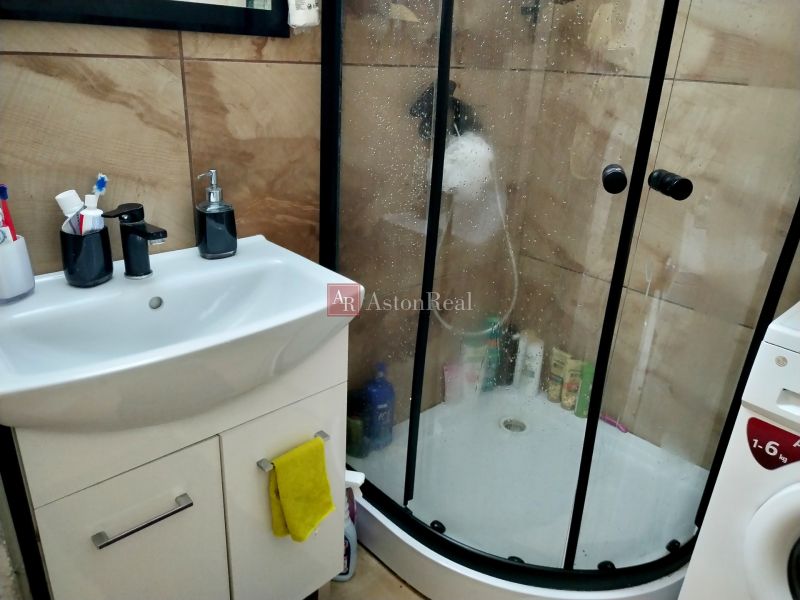 Bathroom in a 2-room apartment with a sink, shower, and washing machine.