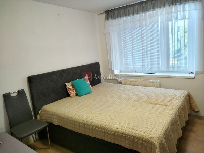Bedroom in a 2-room apartment with a comfortable bed and a large window.