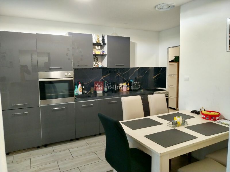 A kitchen in a 2-room apartment with dark gray cabinets and a white table.