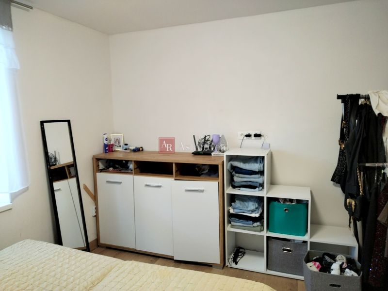 Bedroom in a 2-room apartment with a dresser and a mirror, floor with wooden decor.