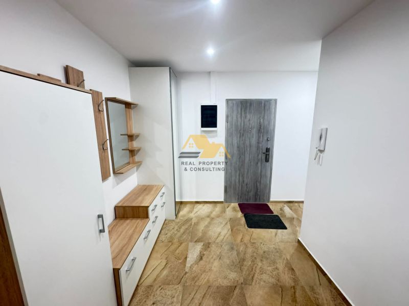 Entrance hall in a 2-room apartment with wood-patterned flooring, a mirror, and a shoe cabinet.