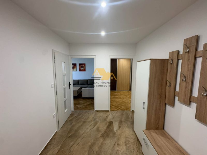 Entrance hall in a 2-room apartment with a wooden decor floor and wall hooks.