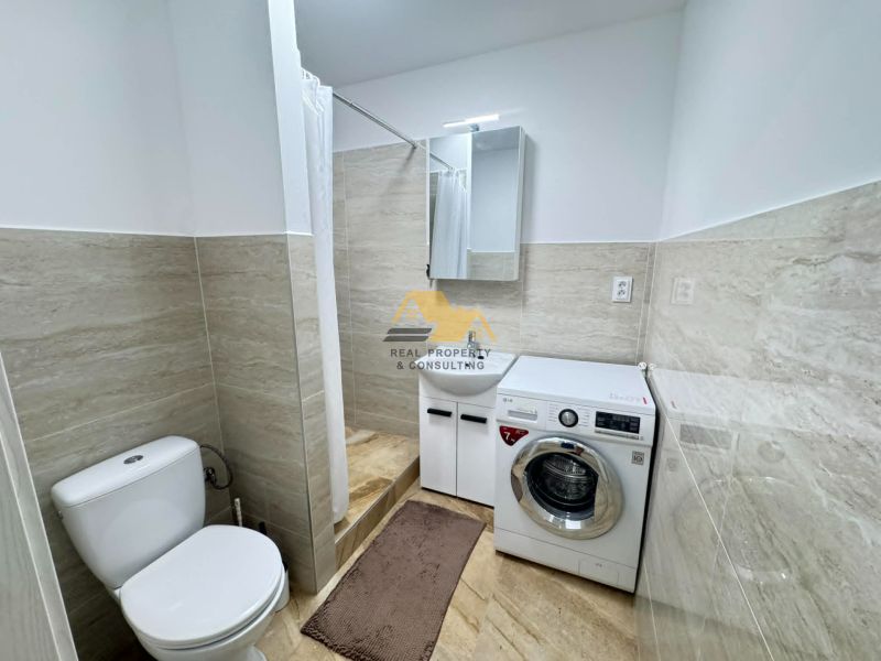A bathroom in a 2-room apartment with a washing machine, shower, and modern tiles.