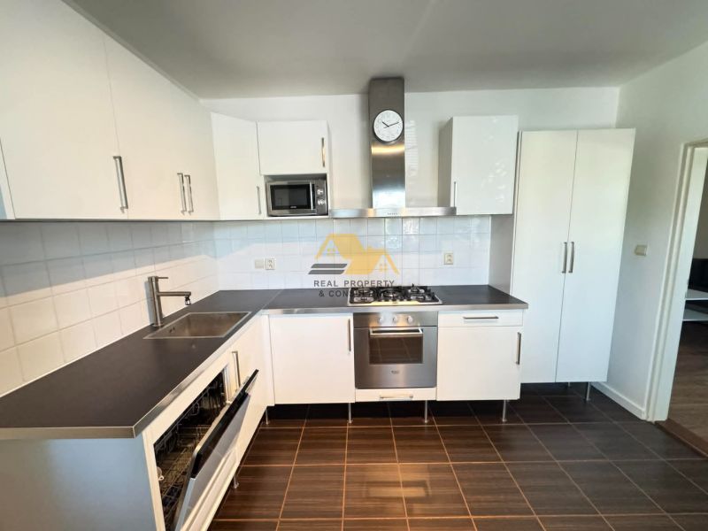 A kitchen in a 3-room apartment with white cabinets and a dark countertop.