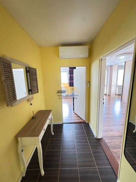 A yellow hallway with a table, mirror, and air conditioning in a 3-room apartment.